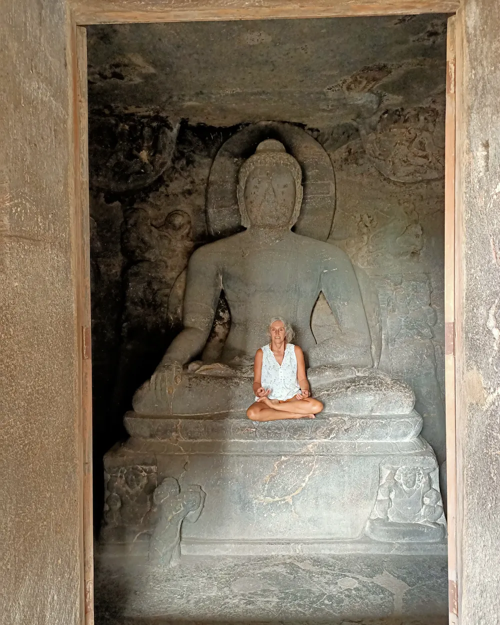 Christel en méditation au pied d’un Bouddha sculpté, dans une grotte d’Ellora