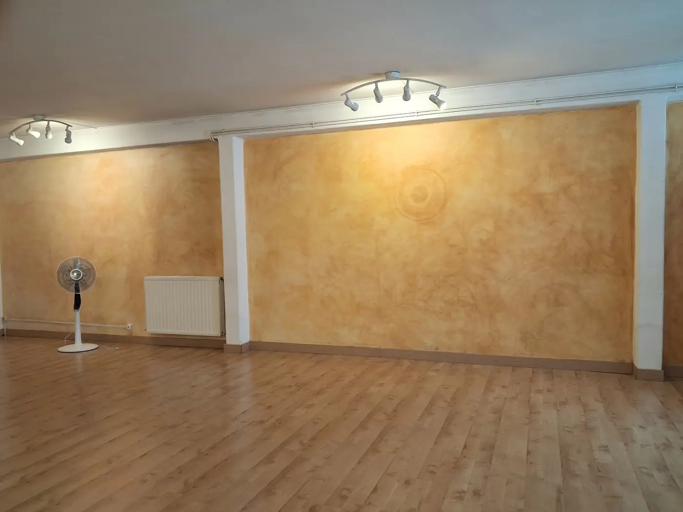 Le grand mur ocre de la salle, éclairé par des spots