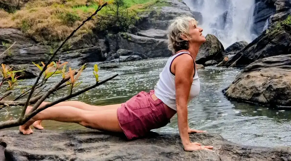Posture du cobra sur un rocher, devant une cascade
